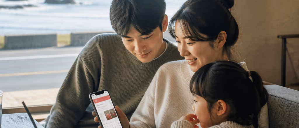 외국인 가족이 스마트폰 숙소 예약 앱으로 제주 펜션을 검색하는 결정적 순간