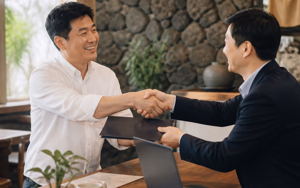 제주 식당 사장님이 완성된 사진과 영상이 담긴 서류철을 받아 들고 담당자와 악수하는 장면